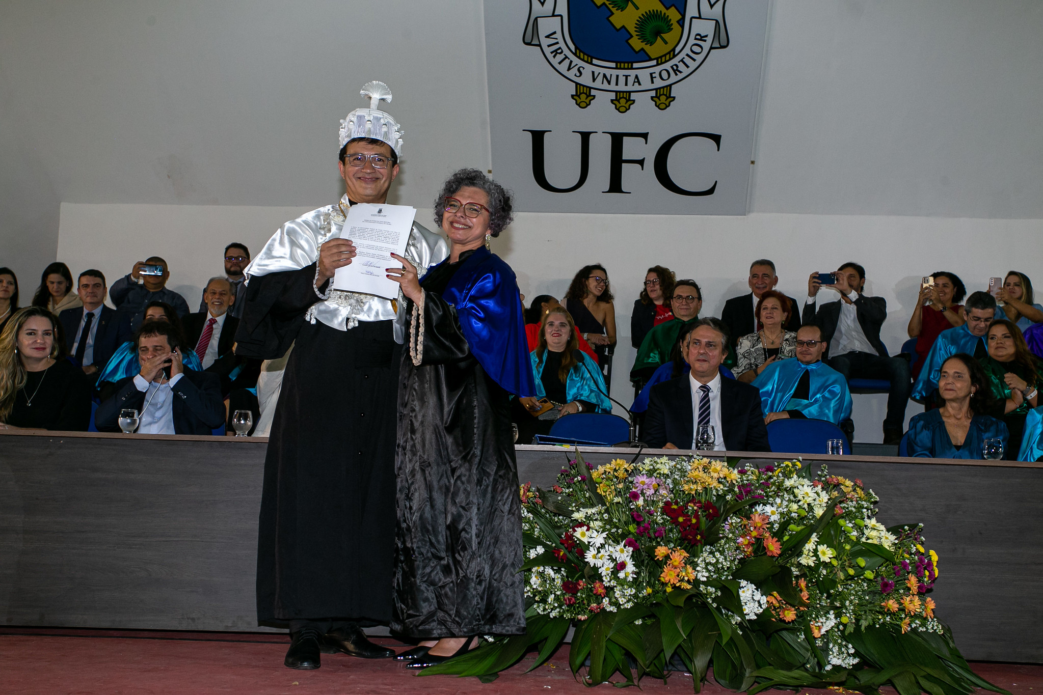 Imagem: O reitor Custódio Almeida e a vice-reitora Diana Azevedo, de vestes talares, posam com o diploma de posse durante solenidade na Concha Acústica da Reitoria. (Foto: Viktor Braga/ UFC Informa)