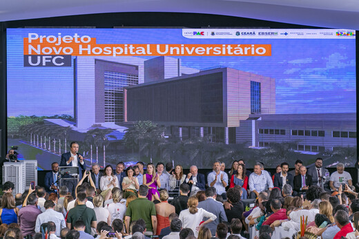 Imagem: Ministro Camilo Santana discursa para o público à frente de um telão com o projeto arquitetônico do novo hospital universitário. (Foto: Álvaro Graça Jr./ UFC Informa) 