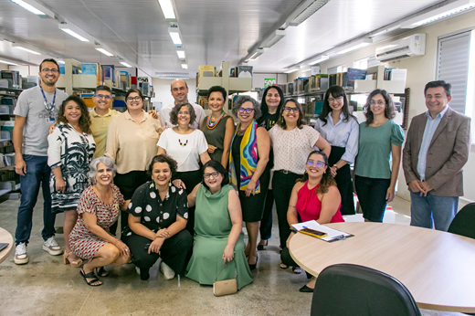 Imagem: Homens e mulheres agachados na frente das prateleiras da Biblioteca da Pós-Graduação em Engenharia. (Foto: Álvaro Graça Jr./ UFC Informa)