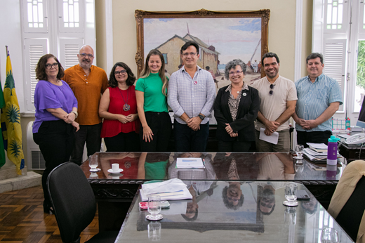 Imagem: De pé, no gabinete do Reitor (da esq. para a dir.): Carla da Escóssia (PROCULT), Prof. Sandro Gouveia (PROCULT), Eulália Camurça (PROCULT),  secretária Yrwana Albuquerque, reitor Custódio Almeida, vice-reitora Diana Azevedo, Prof. Marcelo Soares (LABOMAR) e Prof. Rodrigo Maggioni (LABOMAR).