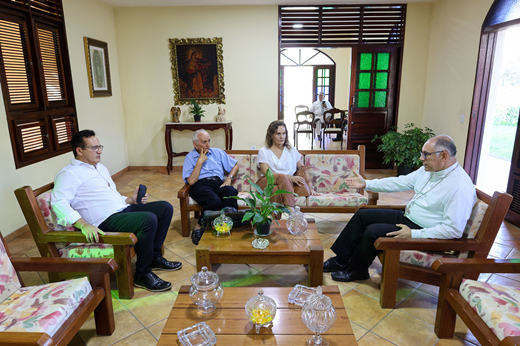 Sentados em sofás na Arquidiocese de Fortaleza, os quatro participantes da reunião discutem.