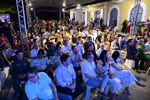 Imagem: Sentado em cadeiras, o público prestigia a programação da solenidade de inauguração