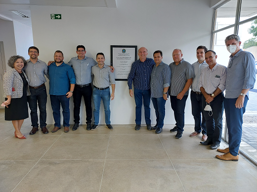 Foto mostra diversas pessoas em pé, olhando para a câmera e com placa de inauguração de laboratório no centro da foto