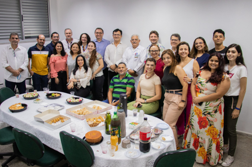 Imagem: um grupo de pessoas reunidas em torno de uma mesa e posando para a foto 