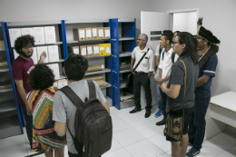 Imagem: Pessoas em pé, conversando próximo a uma estante com arquivos do Nudoc (Foto: Arlindo Barreto/UFC)