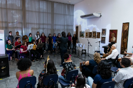 Imagem: foto de pessoas sentadas assistindo a apresentações artíticas