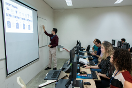 Imagem: Professor apontando o quadro expositivo em sala de aula, com alunos sentados nas cadeiras, assistindo à aula (Foto: Viktor Braga/UFC)