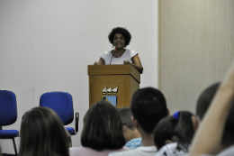 Imagem: Professora Zelma Madeira, em pé, no púlpito, proferindo palestra no auditório da Reitoria da UFC 