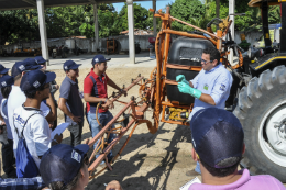 Imagem: Foto de instrutor e alunos do minicurso ao lado de um trator