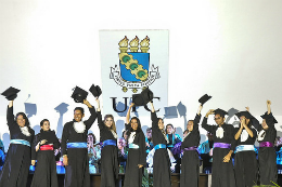 Foto de concludentes no palco da Concha Acústica levantando seus capelos