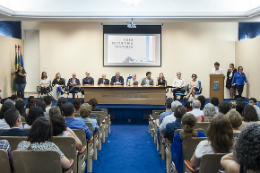 Iamegm: Foto do auditório a partir do fundo, onde vê-se todas as cadeiras ocupadas e a mesa com autoridades no palco