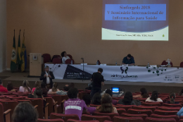 Imagem: Foto do auditório a partir do fundo, com vista para mesa 