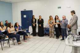 Imagem: Foto de sala de aula do curso com servidores sentados e, de pé, o reitor, a pró-reitora, o professor 