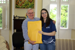 Imagem: Em nome da Seara e do Planetário do Dragão, Sarah Leitão Melo entregou ao reitor um kit com publicações e jogos educativos sobre astronomia (Foto: Heliomárzio Moreira)