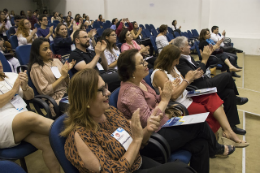 Imagem: Pessoas sentadas nas cadeiras do auditório, formando uma plateia, batendo palmas (Foto: Viktor Braga/UFC)