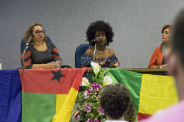 Imagem: Foto da estudante Eveline Amado falando na mesa de abertura