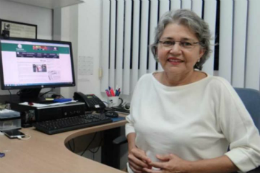 Foto da professora palestranda sentada ao lado de um computador