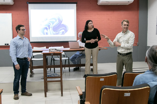 Imagem: Fotografia com os três diplomatas da comitiva norte-americana realizando uma apresentação no auditório do LABOMAR.