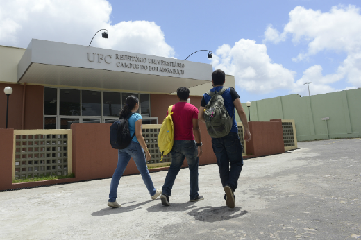 Imagem: Foto de três estudantes de costas andando em frente ao Restaurante Universitário do Campus Porangabuçu