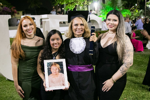 Imagem: quatro mulheres posam para foto. A mais nova, uma criança, segura um porta-retrato com a foto de uma senhora