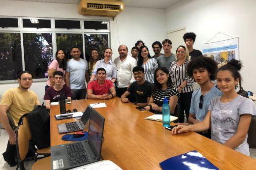 Imagem: Grupo de alunos e professores ao redor de uma mesa, na FACED