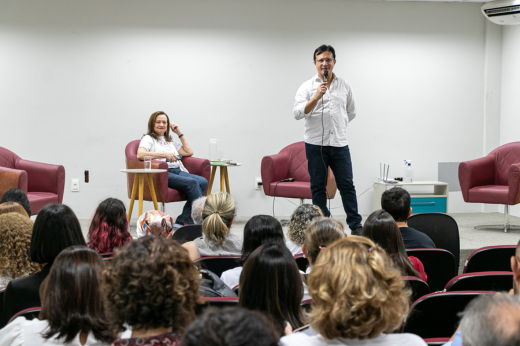 Imagem: Foto do reitor Custódio Almeida em pé no palco segurando o microfone