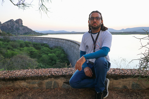 Leandro Rodrigues, estudante de Geografia em Fortaleza, sentado em um parapeito nas proximidades do açude Cedro (Foto: Ribamar Neto/UFC)