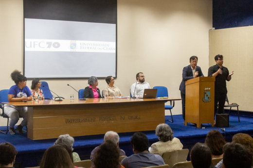 Imagem: Foto da mesa do evento "Estatuinte em Debate", e à direita da imagem, o reitor Custódio Almeida discursa no púlpito