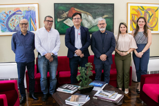 Imagem: Um grupo de quatro homens (entre eles o reitor) e duas mulheres em pé, no Gabinete da Reitoria