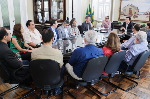 Imagem: reitores, vice-reitora e professores reunidos na mesa de reuniões do Gabinete da Reitoria