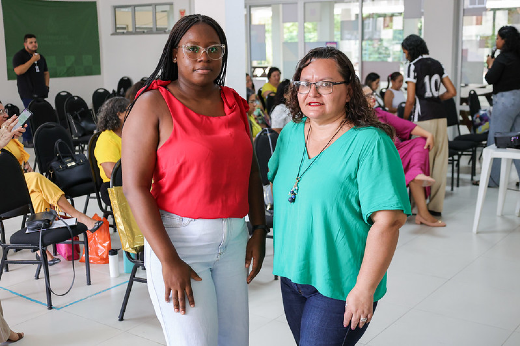 Imagem: mulher negra com blusa verde posa ao lado de mulher negra com blusa vermelha