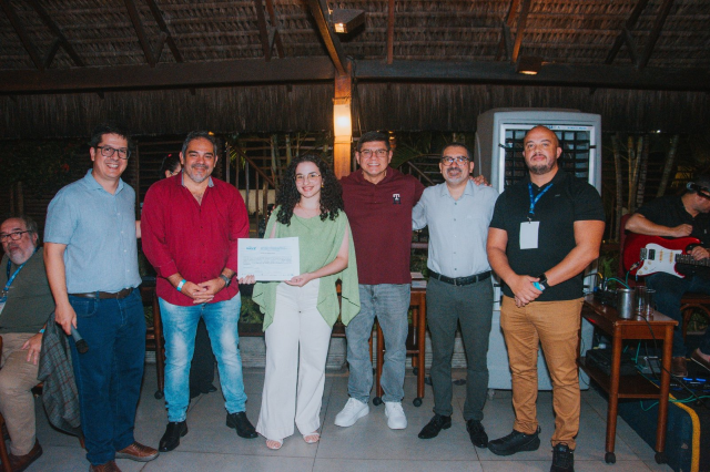 Seis pessoas posam para foto. Ao centro, uma jovem segura um certificado