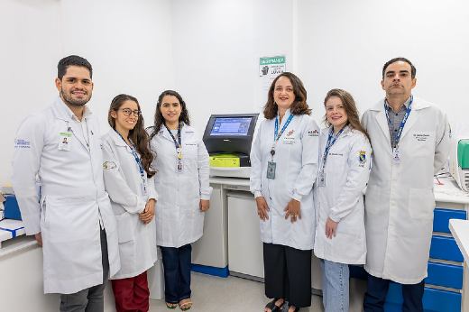 Imagem: foto da equipe do Laboratório de Neuropsicofarmacologia em frente ao equipamento SAMOA, que está em cima de uma bancada atrás da equipe