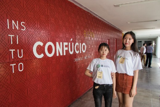 Fotografia de duas jovens em frente à fachada do Instituto Confúcio na UFC