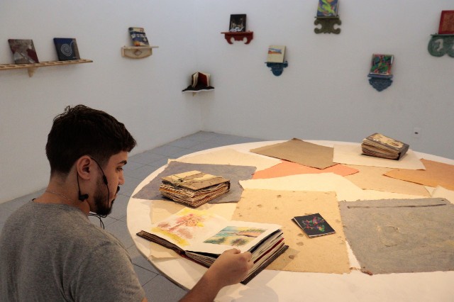 Imagem: Homem folheia livro em ambiente de museu 