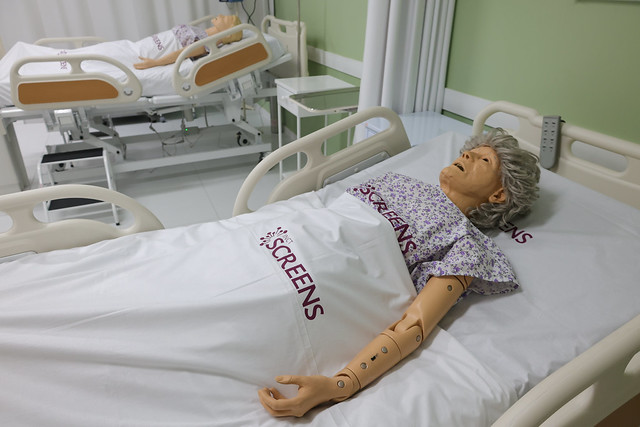 Imagem: Manequim de treinamento deitado em maca hospitalar 