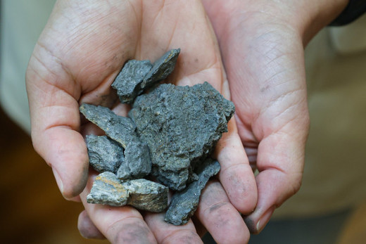 Fotografia em close de mãos segurando minério de grafita (Foto: Ribamar Neto/UFC)