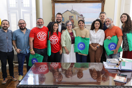 Pessoas reunidas posando para a foto atrás da mesa do reitor