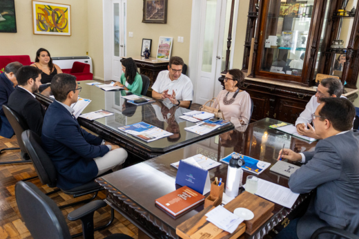 Pessoas sentadas na mesa da Reitoria em reunião com o reitor