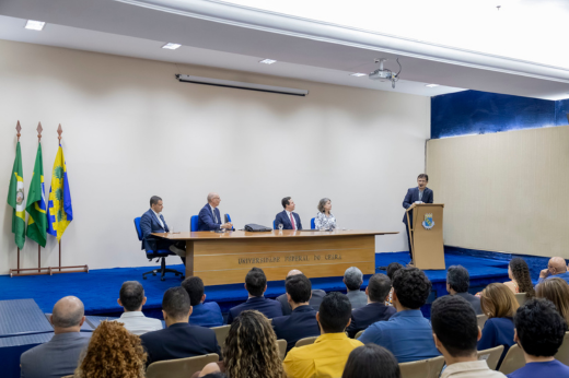 Imagem: Foto do Auditório da Reitoria da UFC com destaque para a mesa e o reitor Custódio discursando no púlpito