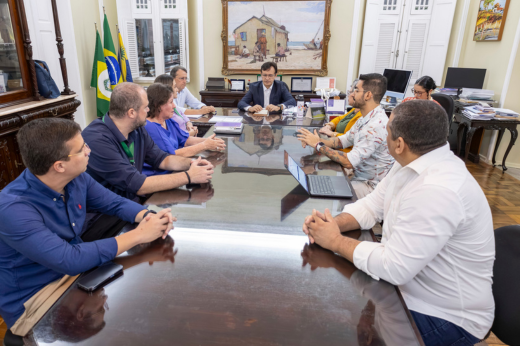 Imagem: Mesa de reunião do Gabinete da Reitoria com o reitor Custódio Almeida sentado na ponta da mesa