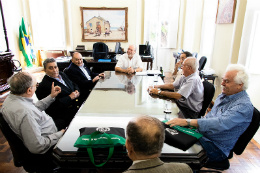 Imagem dos integrantes da Academia ao redor da mesa, na Reitoria, com reitor no fundo