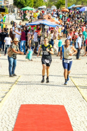 Imagem: foto da professora Camilla e do servidor técnico Erivaldo se aproximando da linha de chegada da corrida