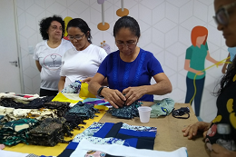 Senhora costurando com materiais em cima de uma mesa