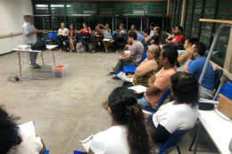 Pessoas reunidas em sala de aula ao redor de um professor 