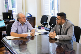 Foto do reitor Cândido Albuquerque e do vereador Márcio Martins sentados à mesa no gabinete do reitor