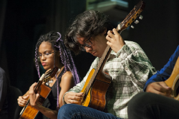 Imagem: foto de uma moça e um rapaz tocando violão