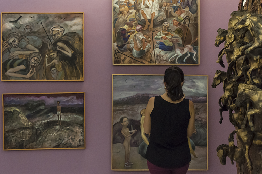 Imagem: Foto de mulher de costa vendo quadros no Museu da Arte da UFC (Foto: Viktor Braga/UFC)