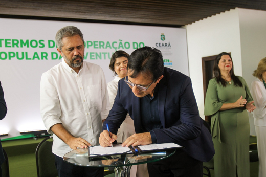 Imagem: O Governador Elmano de Freitas (à esq.) e o reitor Custódio Almeida (à dir.) assinam o termo de cooperação técnica para a implantação do Escritório Popular da Juventude. (Foto: ZeRosa Filho)