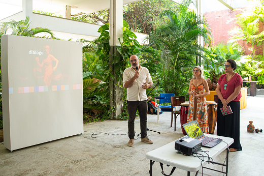 Imagem: Ao lado de projeção em telão no Centro de Convivência, o pró-reitor Sandro Gouveia (à esq.) fala aos servidores junto com a pró-reitora-adjunta Glícia Pontes. (Foto: Viktor Braga/ UFC Informa)